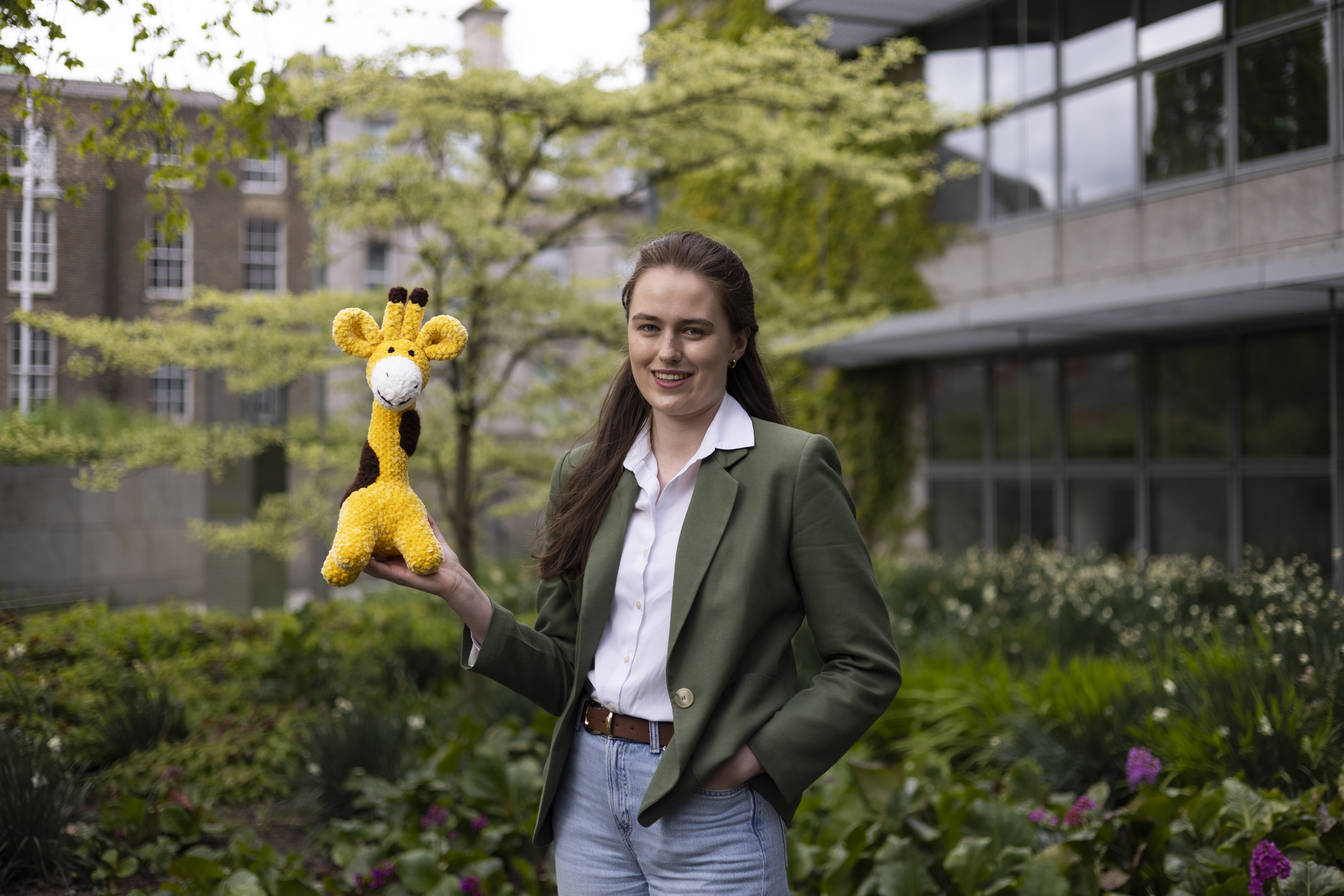Wonky Woolins Owner Image shows Business owner CHloe gradiner holding up a handmade giraffe soft toy made by her company the Wonky Woolins